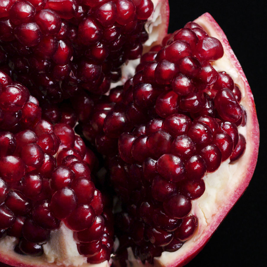 Aveda image: close up of open pomegranate. Black background