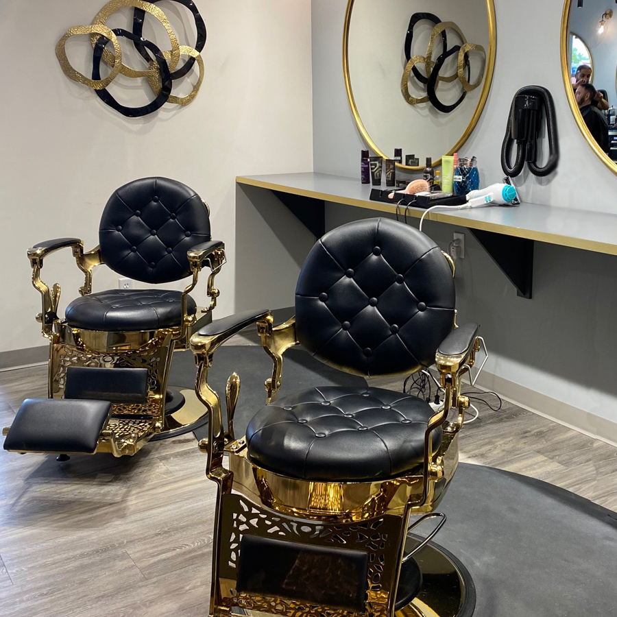 barbershop setup at SOHO BARBERSHOP, SPA & HAIR STUDIO featuring two black leather with gold accents barber chairs